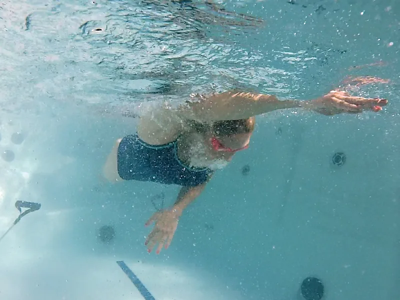 Person swimming against the current inside a swim spa