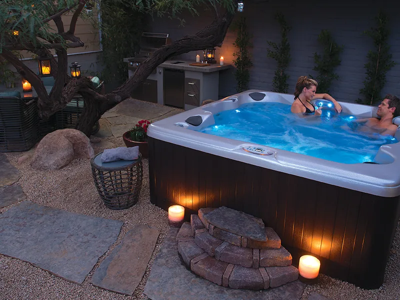 Hot tub lit at twilight on a stone patio surrounded by candles